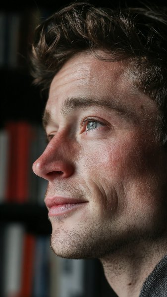 Молодой человек в домашнем офисе: серьезный взгляд и книжные полки. Генерация из нейросети Миджорни