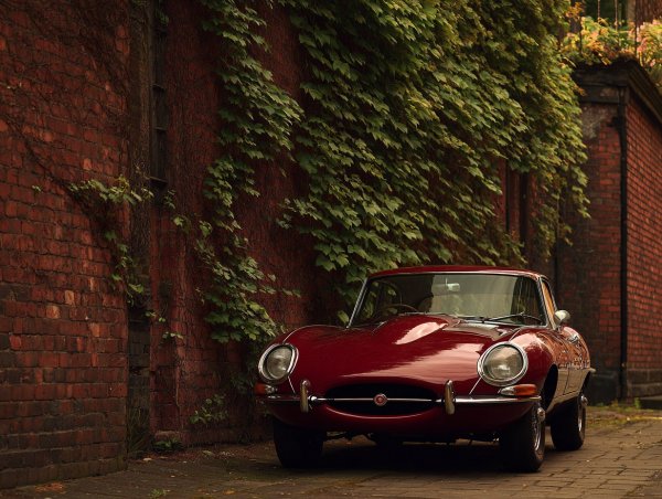 Красный Jaguar E-Type: вне времени и элегантности рядом с кирпичной стеной. Картинка из нейросети Миджорни