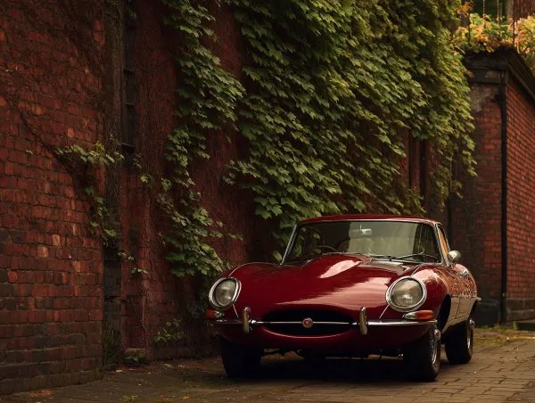 Красный Jaguar E-Type: вне времени и элегантности рядом с кирпичной стеной. Картинка из нейросети Миджорни